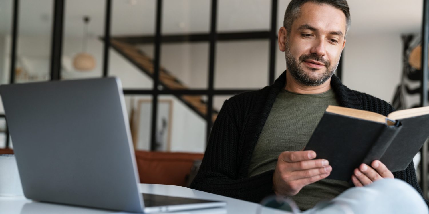 Confident young businessman reading book in the office